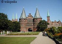 Das Holstentor in L�beck, im Hintergrund sind die Salzspeicher zu sehen  -   F�r eine gr��ere Darstellung bitte auf das Bild klicken.